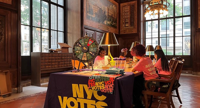 Youth Ambassadors sit at an NYC Votes table at the New York Public Library.